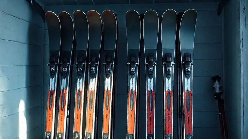 A photorealistic image of cross-country skis neatly stored on a rack in a cool, dry ski room, with a thick layer of storage wax visible on the bases, illuminated by soft, natural light. Professional photography, 8K, cinematic lighting, sharp focus on the skis, depth of field, shot on a high-end DSLR.