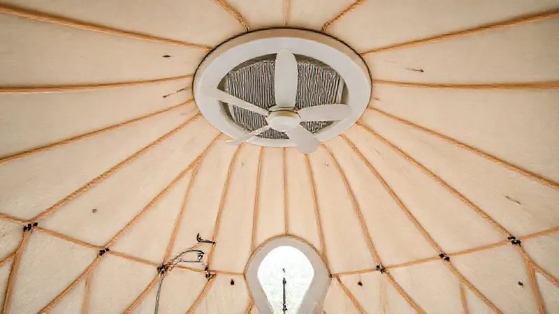 A photorealistic interior shot of a glamping geodome, showcasing a sleek, modern exhaust fan integrated into a bathroom ceiling and a subtle, well-designed floor vent. The dome interior is bright and airy, suggesting excellent air circulation. professional photography, 8K, cinematic lighting, sharp focus, depth of field, shot on a high-end DSLR