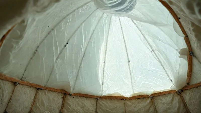 A photorealistic close-up view inside a geodome under construction, showing a translucent vapor barrier being meticulously installed over an insulation layer, with seams expertly taped. The scene emphasizes precision and detail in building envelope integrity. professional photography, 8K, cinematic lighting, sharp focus, depth of field, shot on a high-end DSLR