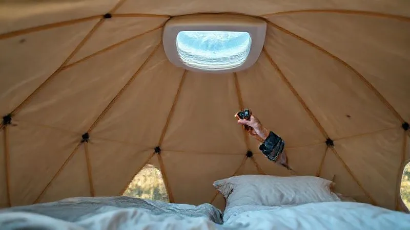 A photorealistic image of a glamping geodome interior, meticulously clean and well-maintained, with a staff member conducting a routine inspection, checking a vent for airflow with a small anemometer. The lighting is bright and inviting, emphasizing cleanliness. professional photography, 8K, cinematic lighting, sharp focus, depth of field, shot on a high-end DSLR